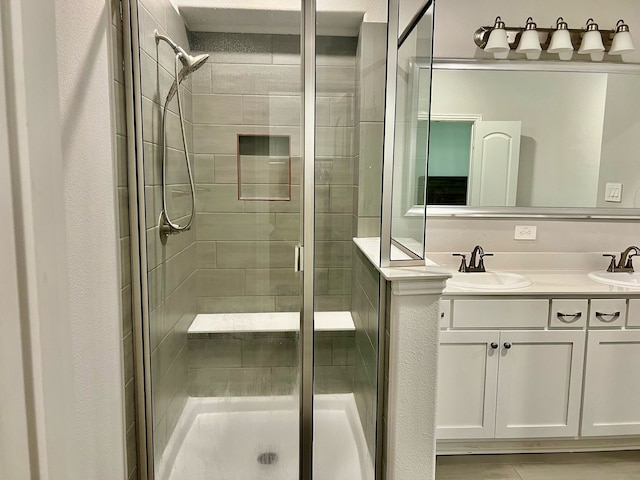 bathroom featuring a stall shower, double vanity, and a sink