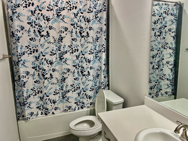 bathroom featuring toilet, a textured wall, shower / bath combo with shower curtain, and vanity