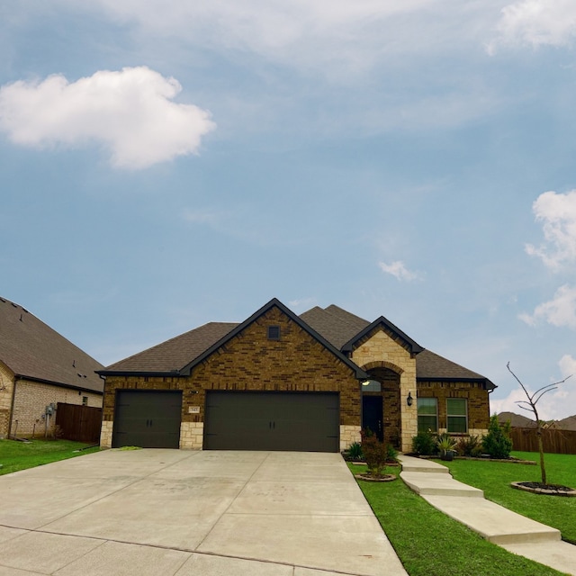 view of front of house featuring a garage, fence, stone siding, a front lawn, and driveway