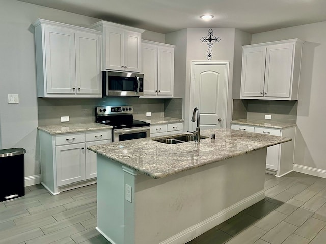 kitchen with baseboards, a sink, appliances with stainless steel finishes, white cabinetry, and wood finish floors