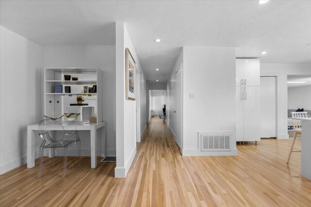 hallway with visible vents, baseboards, recessed lighting, and light wood-style floors