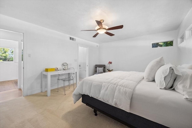 bedroom with visible vents, light colored carpet, and ceiling fan