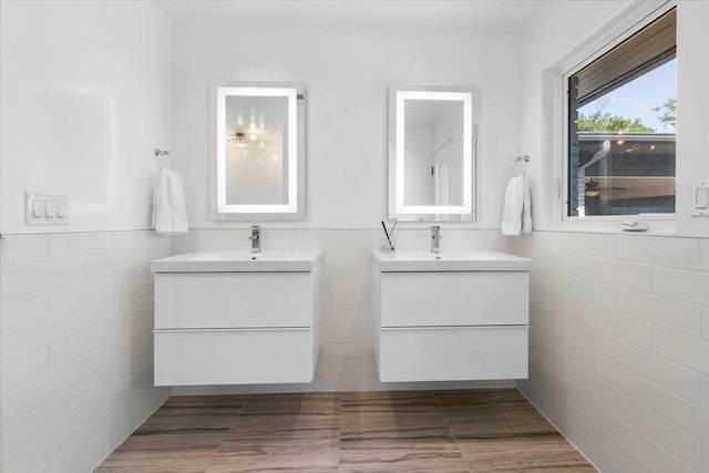 bathroom with two vanities, a sink, and tile walls