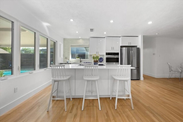 kitchen with a kitchen bar, a kitchen island, white cabinets, and stainless steel appliances