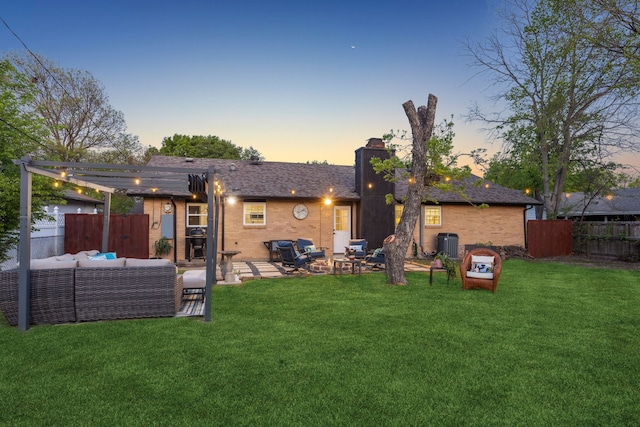 back of house at dusk featuring a chimney, an outdoor living space, a yard, fence, and a patio