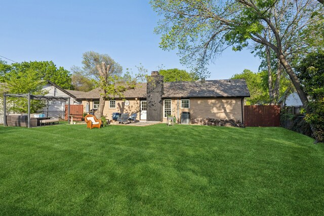 back of property with a lawn, a patio, a chimney, and fence