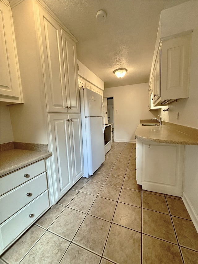 13633 Weald Green St, Dallas, TX 75240 - kitchen with white appliances, a textured ceiling, a sink, light tile patterned flooring, and white cabinetry