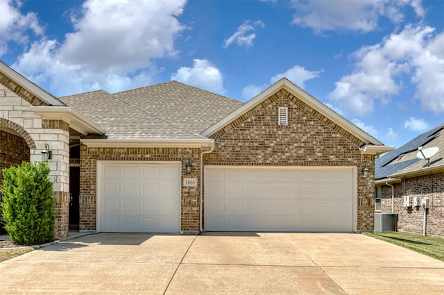 1664 Laramie Ln, Burleson, TX 76028 - view of front facade featuring a garage, central air condition unit, brick siding, a shingled roof, and driveway
