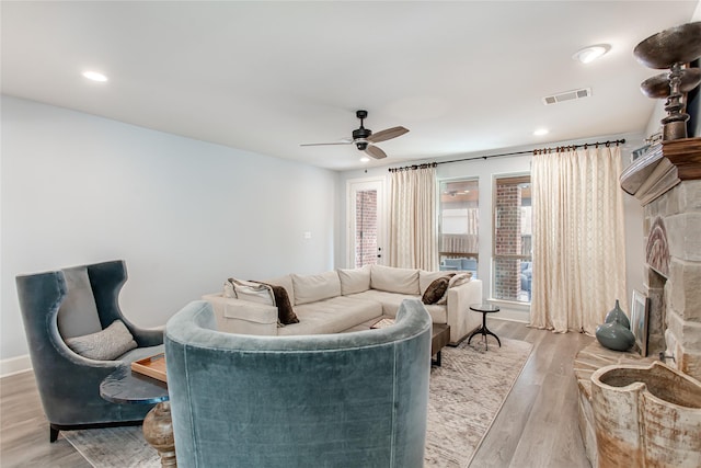living room with light wood-type flooring, visible vents, recessed lighting, a ceiling fan, and a fireplace