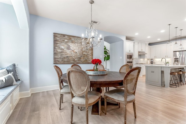 dining space featuring arched walkways, light wood-style floors, visible vents, and recessed lighting