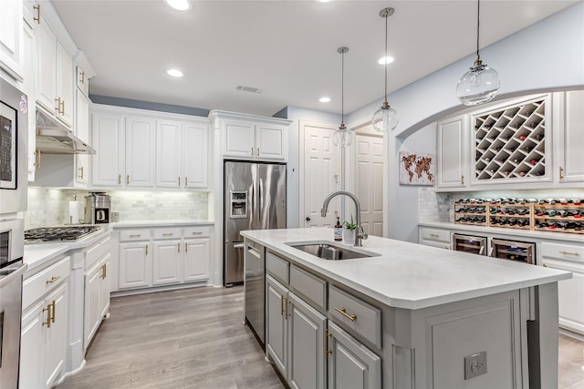 kitchen with white cabinets, an island with sink, gray cabinets, a sink, and tasteful backsplash