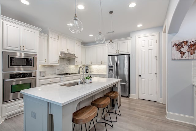 kitchen featuring a sink, stainless steel appliances, white cabinets, under cabinet range hood, and visible vents