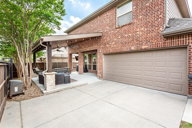 view of patio with concrete driveway, fence, ceiling fan, and a garage