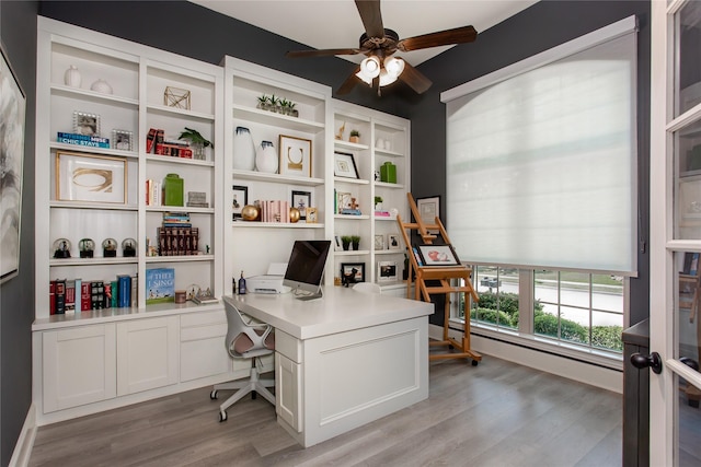 office with light wood-style floors and ceiling fan