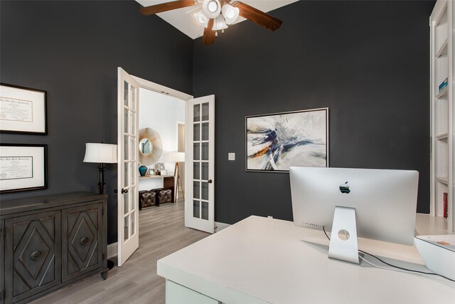 office area with light wood finished floors, french doors, a high ceiling, and ceiling fan