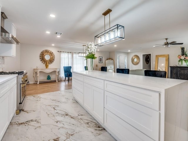 3124 Merrell Rd, Dallas, TX 75229 - kitchen featuring stainless steel range, recessed lighting, light marble finish floors, white cabinets, and light countertops