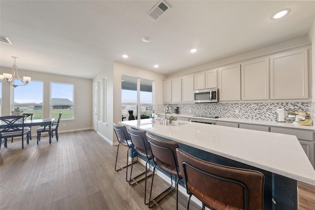 5017 Freestone Dr, Weatherford, TX 76085 - kitchen featuring light wood finished floors, backsplash, visible vents, a sink, and stainless steel microwave