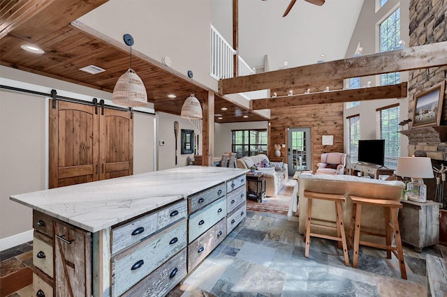 interior space with a ceiling fan, stone tile flooring, a barn door, decorative light fixtures, and wooden ceiling