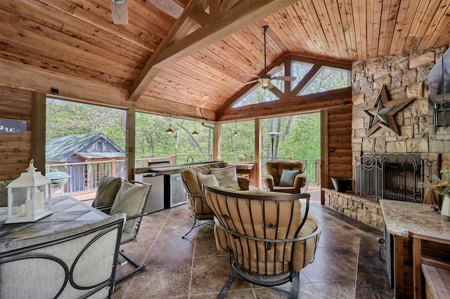 interior space featuring a fireplace, outdoor dining area, beam ceiling, and ceiling fan