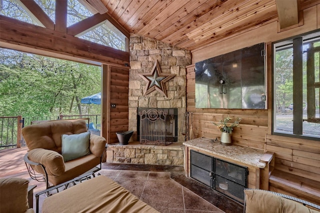 living area with high vaulted ceiling, a fireplace, wood walls, and wooden ceiling