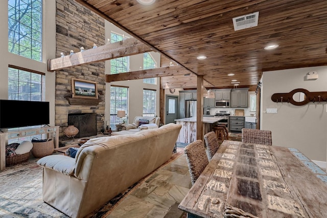 living room featuring stone tile flooring, wood ceiling, visible vents, and plenty of natural light
