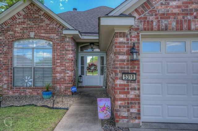 5310 Lucerne Ln, Bossier City, LA 71112 - view of exterior entry with brick siding, an attached garage, and roof with shingles