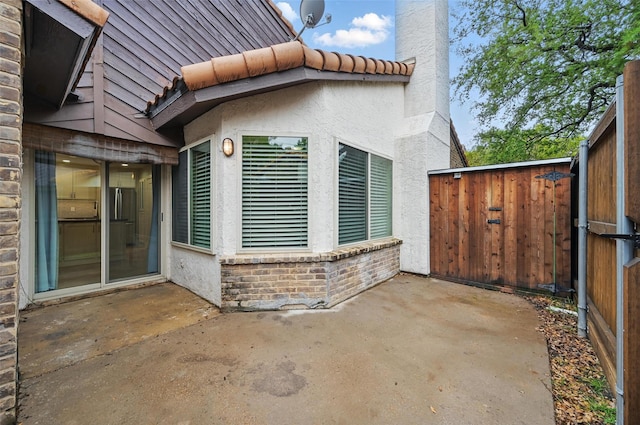 exterior space with a tile roof, fence, a patio, and a chimney