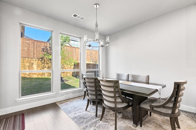 dining area featuring baseboards, visible vents, wood finished floors, and a notable chandelier