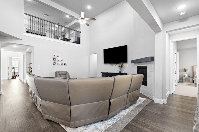 living room with baseboards, a ceiling fan, a glass covered fireplace, and wood finished floors