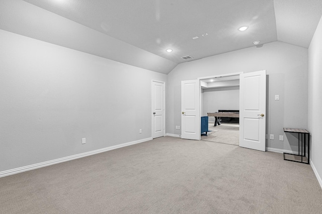 unfurnished bedroom with baseboards, lofted ceiling, visible vents, and light colored carpet