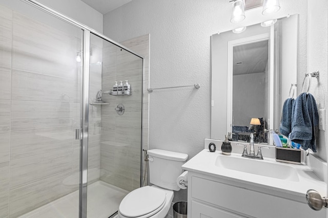 full bathroom featuring vanity, a textured wall, a stall shower, and toilet