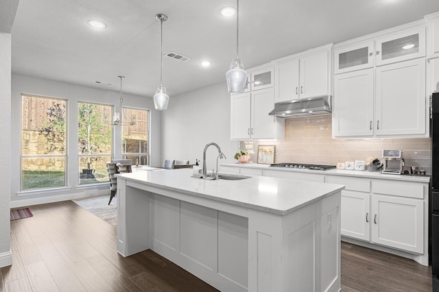 kitchen featuring visible vents, under cabinet range hood, a sink, backsplash, and stainless steel gas stovetop