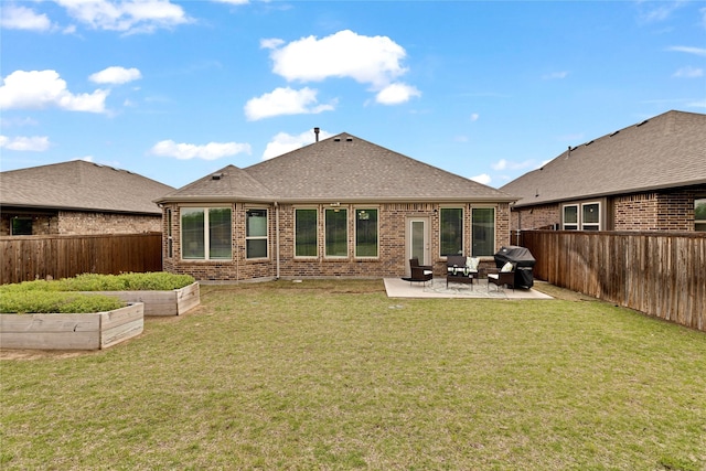 back of property with a fenced backyard, a garden, brick siding, and a patio