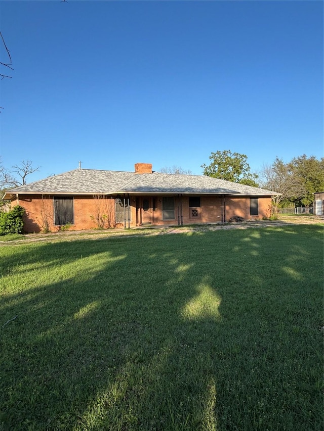 rear view of house with a chimney and a lawn