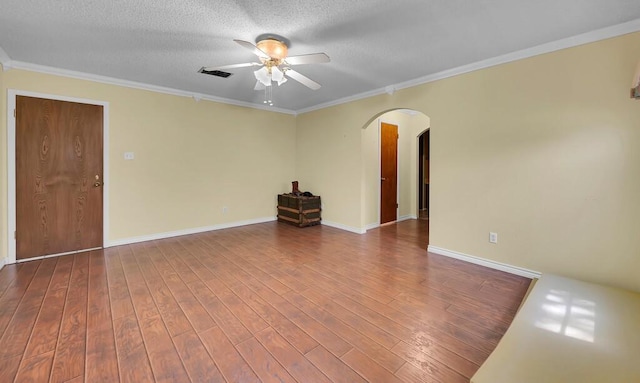 spare room with a textured ceiling, a ceiling fan, visible vents, arched walkways, and wood finished floors