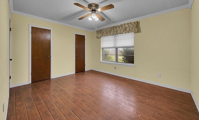 unfurnished bedroom featuring baseboards, two closets, dark wood finished floors, crown molding, and a textured ceiling