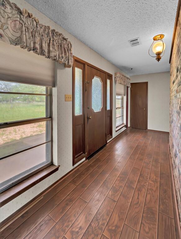 foyer with visible vents, a textured ceiling, and dark wood finished floors