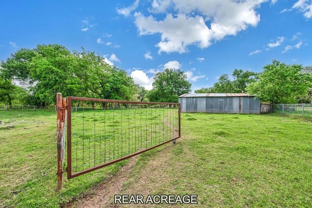 view of yard with an outbuilding, a pole building, fence, and a rural view
