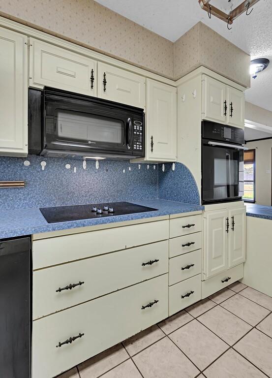 kitchen featuring white cabinetry, black appliances, and light tile patterned flooring