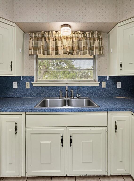 kitchen featuring white cabinetry, a sink, and decorative backsplash