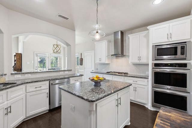 619 Southwestern Dr, Rockwall, TX 75087 - kitchen with wall chimney range hood, stainless steel appliances, a center island, white cabinetry, and recessed lighting