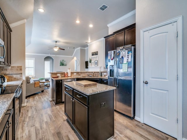 kitchen with crown molding, a peninsula, tasteful backsplash, a ceiling fan, and appliances with stainless steel finishes