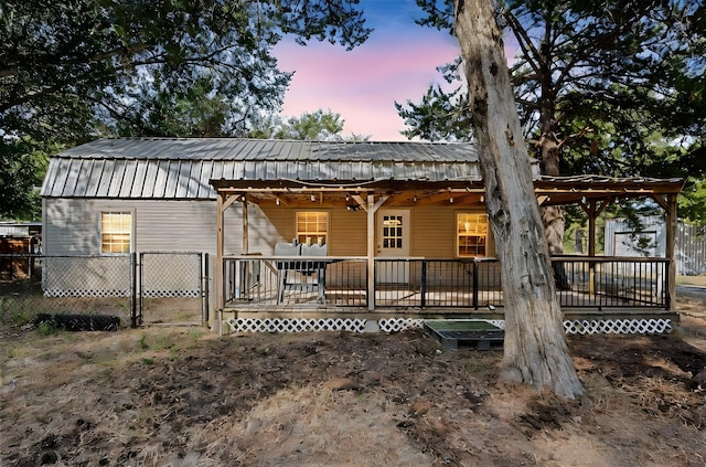 rear view of property featuring a porch, metal roof, fence, and a gate