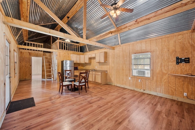 dining space featuring ceiling fan, light wood finished floors, cooling unit, wood walls, and high vaulted ceiling