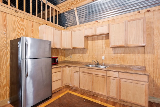 kitchen with light brown cabinets, light countertops, freestanding refrigerator, light wood finished floors, and a sink