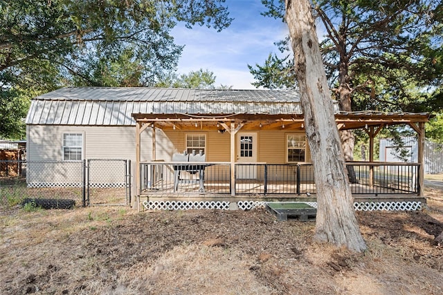 back of house featuring metal roof, fence, and a gate