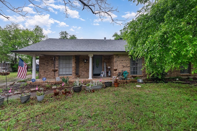 back of property featuring brick siding, a shingled roof, covered porch, and a yard
