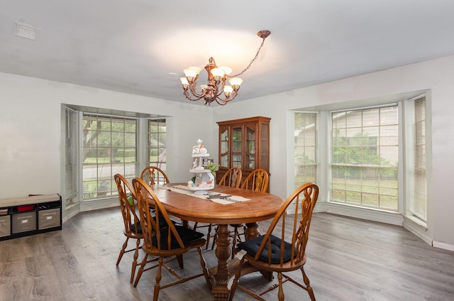 dining area featuring a chandelier, a wealth of natural light, visible vents, and wood finished floors