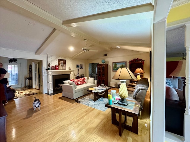 2124 Parkhaven Dr, Plano, TX 75075 - living room featuring ceiling fan, a textured ceiling, light wood finished floors, a large fireplace, and vaulted ceiling with beams