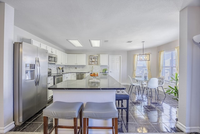 3144 Longbow Dr, Grand Prairie, TX 75052 - kitchen with decorative backsplash, a breakfast bar, baseboards, white cabinetry, and stainless steel appliances